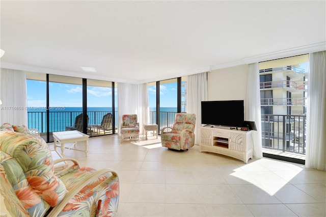 living room featuring light tile patterned floors, a water view, and a wall of windows