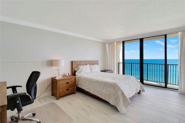 bedroom with a textured ceiling, floor to ceiling windows, a water view, and crown molding