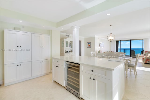 kitchen with white cabinetry, a center island, a wall of windows, wine cooler, and pendant lighting