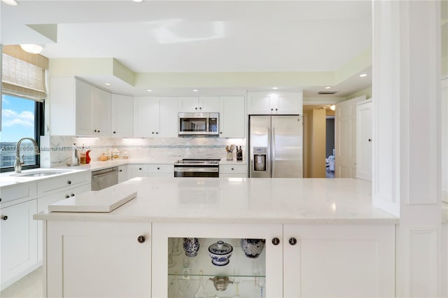 kitchen with light stone countertops, white cabinetry, sink, and stainless steel appliances