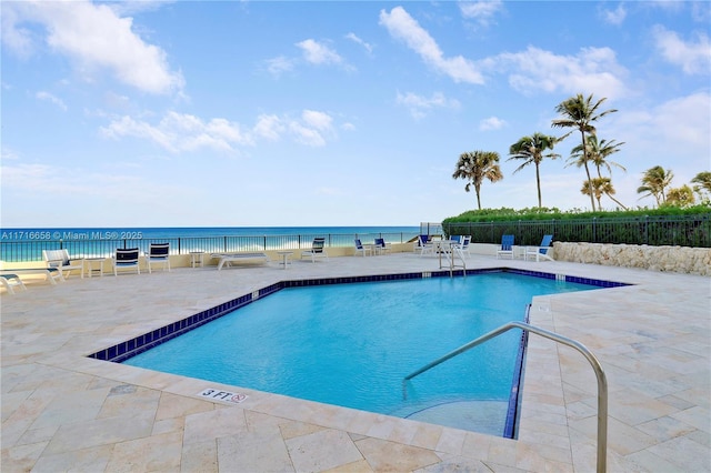 view of pool with a water view and a patio