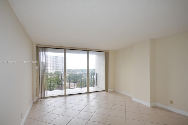 spare room featuring light tile patterned floors, expansive windows, baseboards, and a textured ceiling