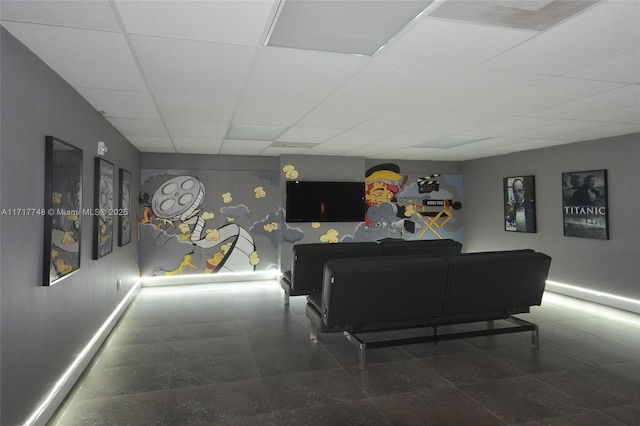 living area featuring a paneled ceiling and baseboards