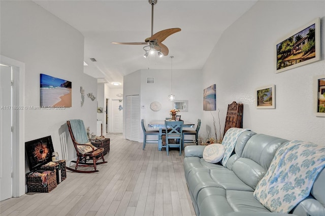 living room with a ceiling fan, visible vents, vaulted ceiling, and light wood finished floors