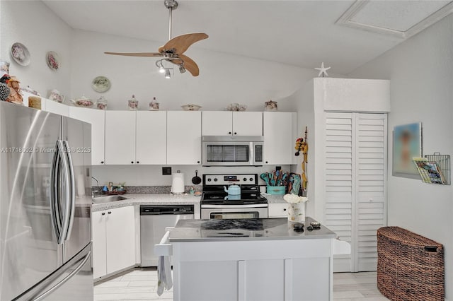 kitchen with stainless steel appliances, a kitchen island, light countertops, and white cabinets