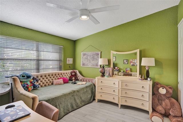 bedroom featuring a textured wall, light wood-type flooring, vaulted ceiling, and a textured ceiling