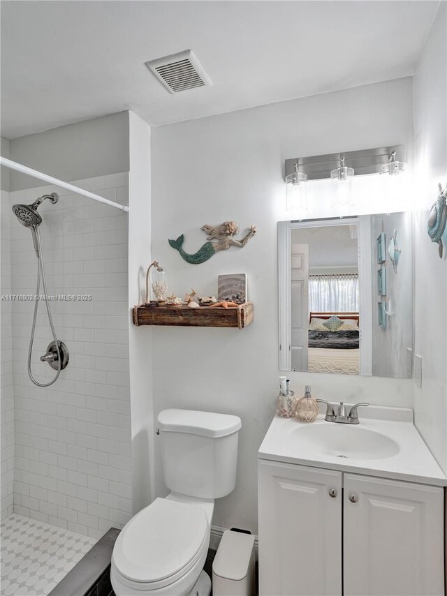 bathroom featuring tiled shower, vanity, and toilet