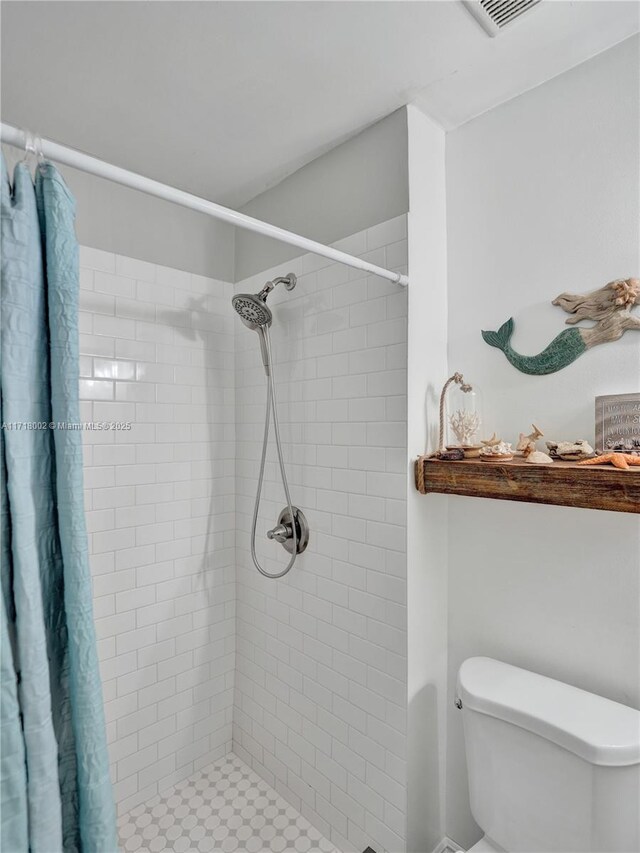 bathroom with a tile shower, vanity, and toilet