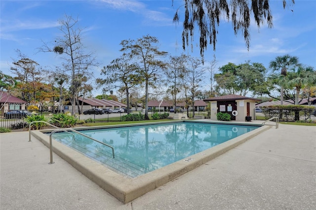 community pool with a patio, fence, and a residential view