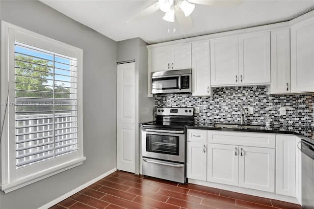 kitchen featuring decorative backsplash, stainless steel appliances, ceiling fan, sink, and white cabinetry