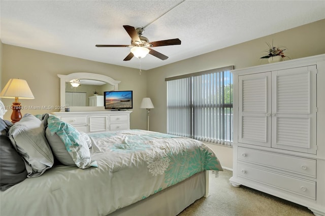 carpeted bedroom featuring ceiling fan and a textured ceiling