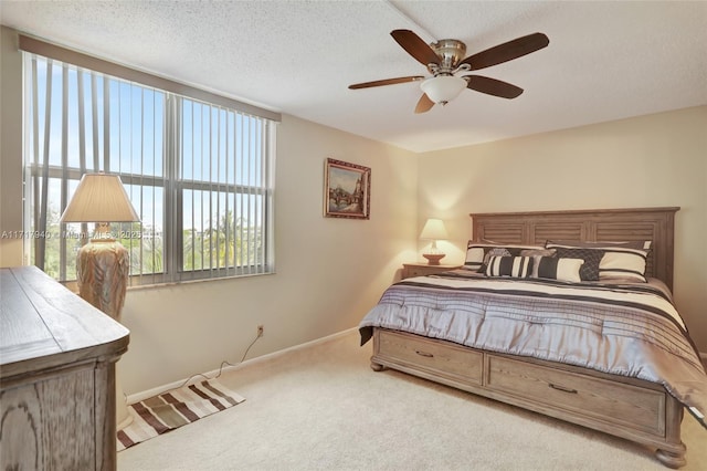 bedroom with a textured ceiling, light colored carpet, and ceiling fan