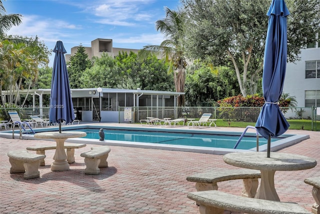 view of swimming pool with a patio area and a sunroom