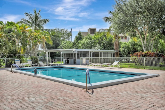 view of swimming pool with a sunroom and a patio