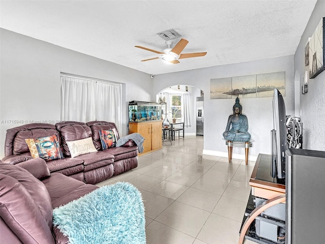 living room featuring a textured ceiling, ceiling fan, and light tile patterned flooring