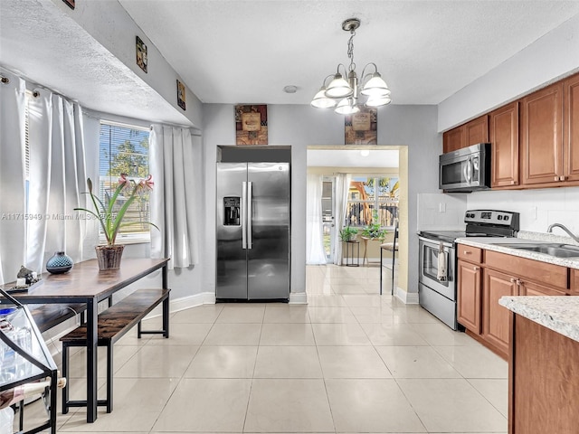 kitchen featuring sink, an inviting chandelier, pendant lighting, a textured ceiling, and appliances with stainless steel finishes