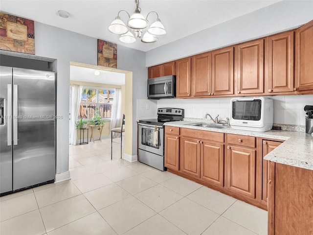 kitchen with pendant lighting, an inviting chandelier, sink, light tile patterned flooring, and stainless steel appliances