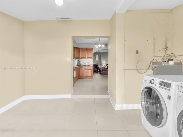 clothes washing area featuring separate washer and dryer, light tile patterned floors, and water heater