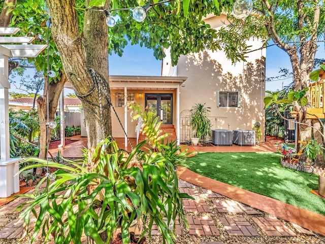 back of property with a lawn, french doors, and cooling unit