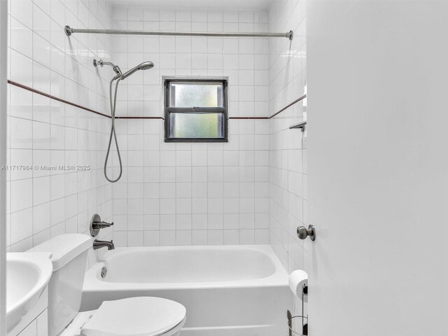 bathroom with toilet and tiled shower / bath