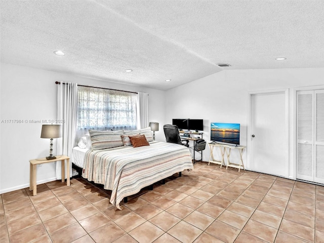 tiled bedroom with a textured ceiling and vaulted ceiling