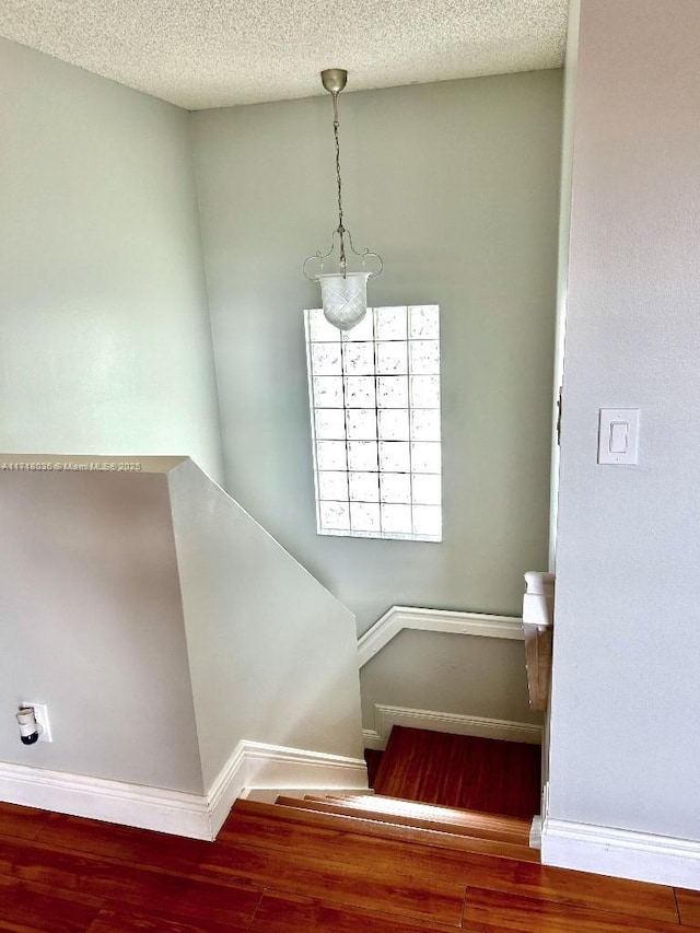 staircase with wood-type flooring and a textured ceiling