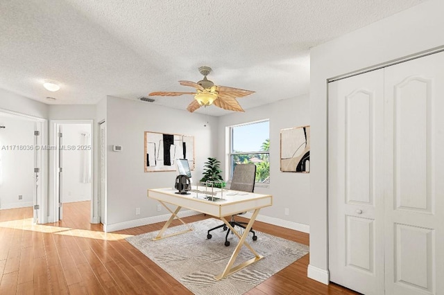 home office with ceiling fan, a textured ceiling, and hardwood / wood-style flooring