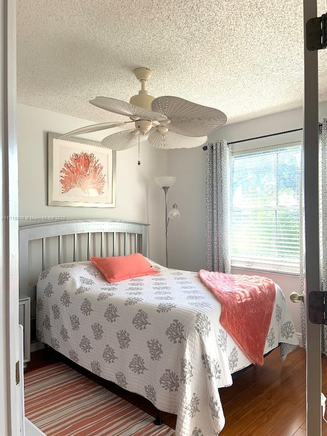 bedroom with ceiling fan, hardwood / wood-style floors, and a textured ceiling