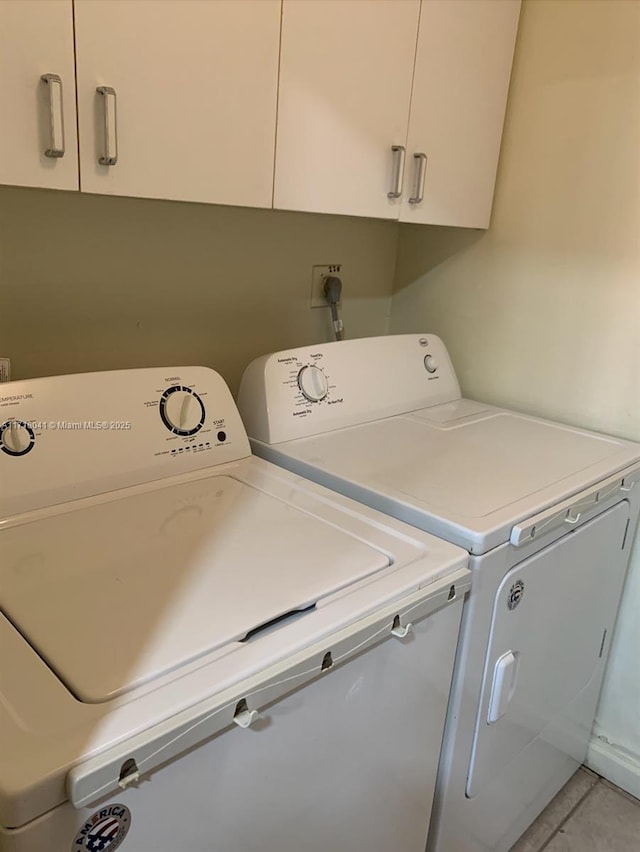 laundry room with tile patterned floors, washing machine and dryer, and cabinets