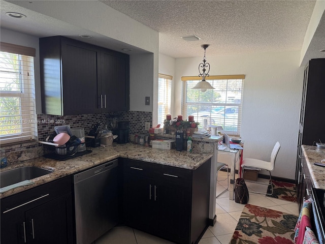 kitchen with light stone countertops, light tile patterned floors, hanging light fixtures, and black dishwasher