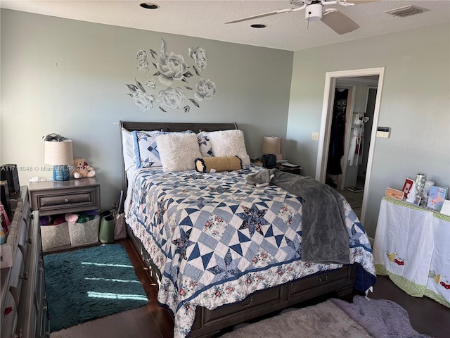 bedroom featuring ceiling fan, wood-type flooring, and a textured ceiling