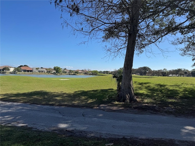 surrounding community with a water view and a lawn