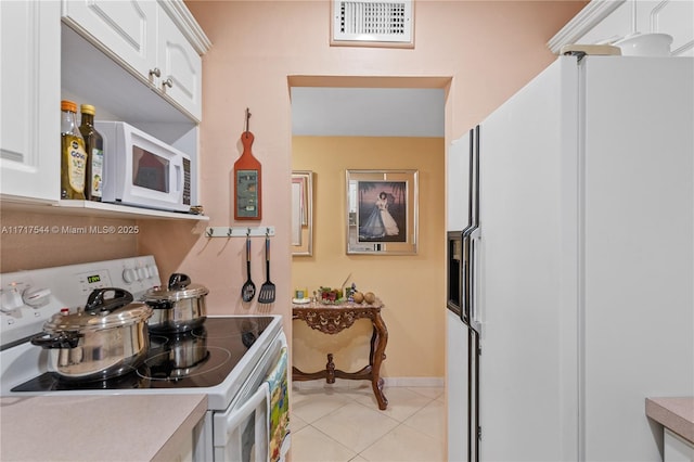 kitchen with white cabinets, light tile patterned flooring, and white appliances