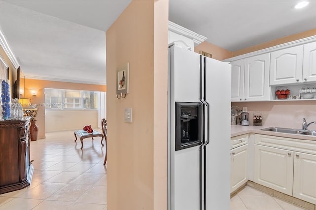 kitchen featuring ornamental molding, sink, white cabinets, white fridge with ice dispenser, and light tile patterned flooring