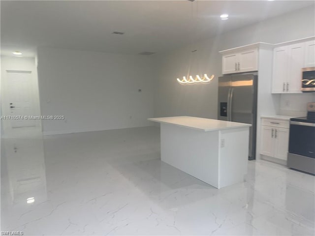 kitchen featuring white cabinets, stainless steel appliances, decorative light fixtures, and a kitchen island