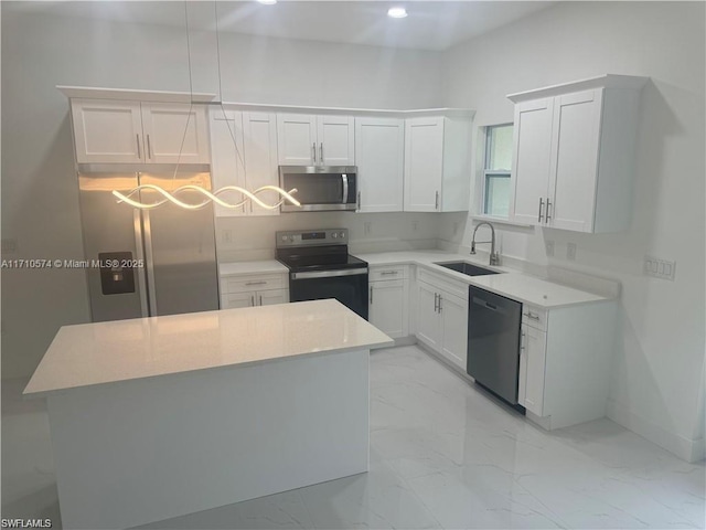 kitchen with white cabinets, appliances with stainless steel finishes, a kitchen island, and sink