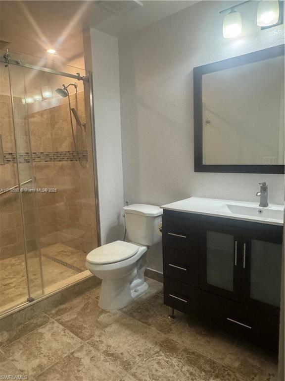 bathroom featuring vanity, toilet, and a shower with shower door