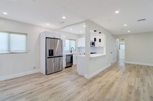 kitchen featuring white cabinets, decorative light fixtures, stainless steel appliances, kitchen peninsula, and light wood-type flooring