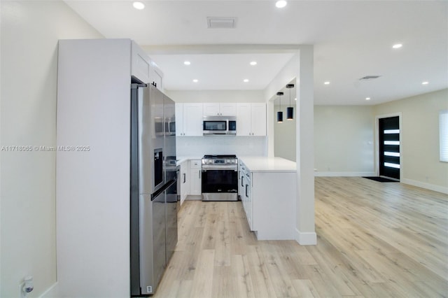 kitchen featuring appliances with stainless steel finishes, tasteful backsplash, white cabinetry, light hardwood / wood-style flooring, and pendant lighting