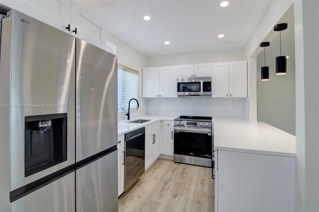 kitchen featuring hanging light fixtures, sink, backsplash, white cabinets, and stainless steel appliances