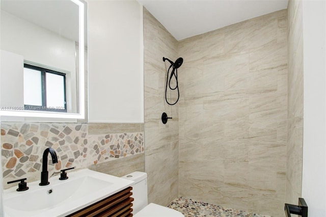 bathroom with tile walls, toilet, vanity, and a tile shower