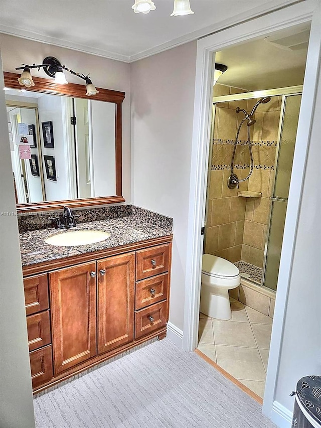 bathroom featuring tile patterned flooring, vanity, toilet, and a shower with door