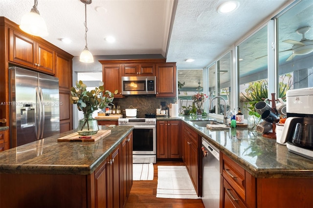 kitchen featuring sink, tasteful backsplash, decorative light fixtures, a kitchen island, and stainless steel appliances