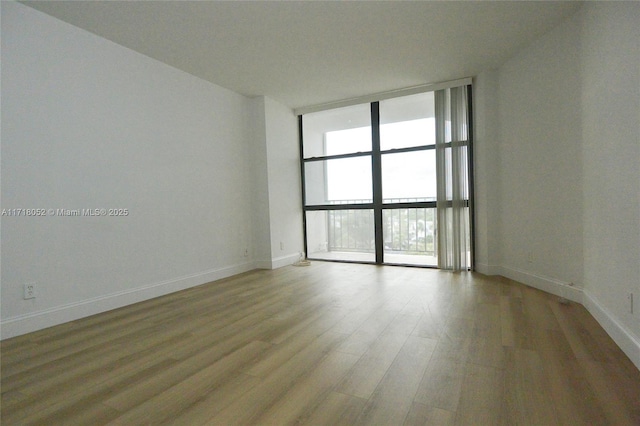 unfurnished room with light hardwood / wood-style floors and expansive windows