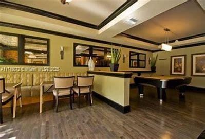 interior space with a tray ceiling, dark hardwood / wood-style floors, and ornamental molding