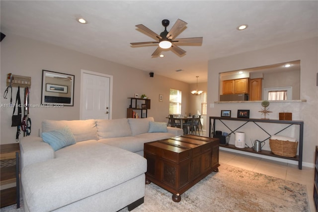 tiled living room with ceiling fan with notable chandelier