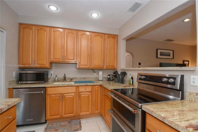 kitchen with light stone countertops, appliances with stainless steel finishes, light tile patterned floors, and sink