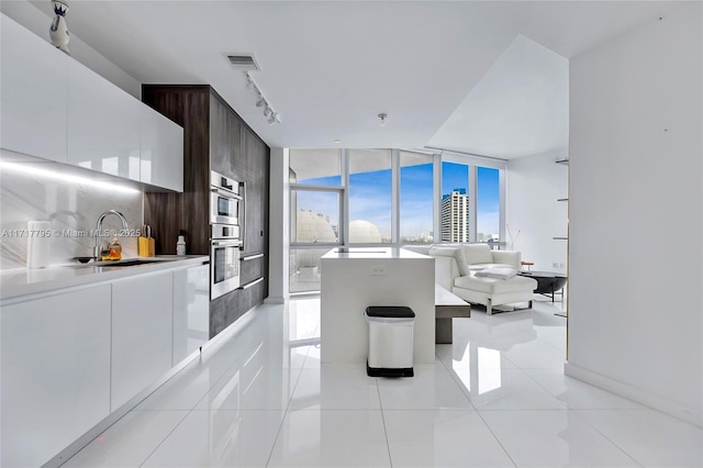 tiled living room with track lighting, floor to ceiling windows, and sink