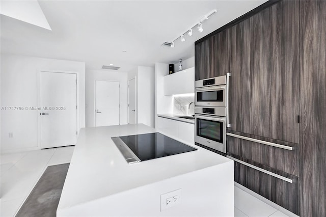 kitchen with light tile patterned floors, modern cabinets, a center island, black electric stovetop, and light countertops