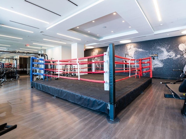 recreation room featuring a raised ceiling, wood finished floors, wallpapered walls, and recessed lighting